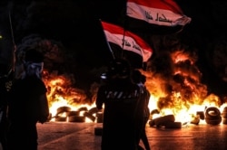 FILE - Anti-government protesters demand free elections and an end to corruption outside the provincial council building in Basra, Iraq, Aug. 17, 2020.
