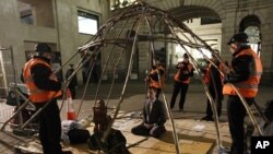 A protester meditates in front of a statue of Buddha as bailiffs lift the frame of his tent from around him during the eviction of the Occupy encampment outside St Paul's Cathedral in London February 28, 2012.