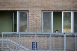 A nurse wearing a sanitary mask watches from a window of the hospital of Codogno, near Lodi in northern Italy, Feb. 21,2020. Health officials reported the country's first cases of contagion of COVID-19 in people who had not been in China.