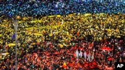 Orang-orang mengaktifkan fitur senter pada perangkat telepon selular mereka dan melapisinya dengan kertas warna-warna bendera Rumania dalam sebuah unjuk rasa anti pemerintah (12/2). Bukares, Rumania. (foto: AP Photo/Vadim Ghirda)