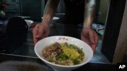 Chef Hung serves pineapple beef noodle at his restaurant in Taipei, Taiwan, March 10, 2021. 