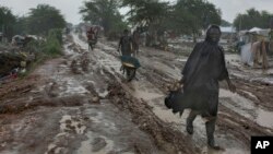 People trudge along the main passageway through United Nations' Malakal Camp for Internally Displaced People, (IDP) during the wet season which has made life for hundreds of thousands of IDPs in South Sudan very challenging, in Malakal, July 24, 2014.