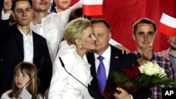 Presiden petahana Polandia Andrzej Duda dipeluk oleh istrinya, Agata Kornhauser-Duda di Pultusk, Polandia Minggu (12/7). 
