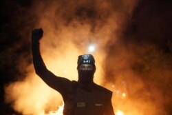 FILE - A protester holds his fist in the air during a protest against racial injustice and police brutality early in the morning on August 23, 2020 in Portland, Oregon.