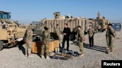 Britain's Prime Minister David Cameron chats with soldiers in front of Mastiff armored vehicles at Camp Bastion, outside Lashkar Gah, in Helmand Province, Afghanistan, Dec. 20, 2012.