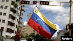 一名抗议者在参加一场抗议马杜罗政府的罢工后站在首都卡拉卡斯的街头高举一面委内瑞拉的旗帜。 （2017年7月29日）