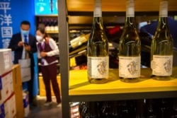 FILE - A staffer and visitor speak near a display of Australian wines at the China International Import Expo in Shanghai, Nov. 5, 2020. China raised import taxes on Australian wine, stepping up pressure on Australia over several disputes.