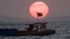 A Cambodian flag on a fishing boat flutters in wind as the sun sets over the Gulf of Thailand near Cambodia's port town of Sihanoukville.