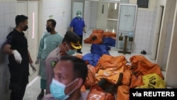 Officers stand near bags containing the bodies of victims of a prison fire at a local hospital, following a fire overnight at an overcrowded jail in Tangerang, Indonesia, Sept. 8, 2021. (Antara Foto/Muhammad Iqbal/via Reuters) 