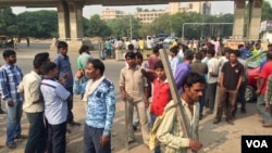 Scores of daily wage workers wait at a major street intersection in the business hub of Gurgaon near New Delhi hoping to find work. (A. Pasricha/VOA)