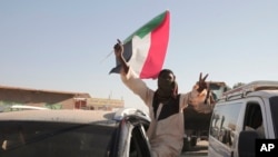 A man with a Sudanese flag gestures following reports that Sudan's army had entered the central city of Wad Madani and pushed out its paramilitary rivals, the Rapid Support Forces, in Merowe, Sudan, Jan.11, 2025.