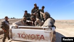 Islamic State fighters sit on a pickup truck while being held as prisoners by fighters of the Syrian Democratic Forces near Ash Shaddadi, Hasakah province, Syria, Feb. 18, 2016.