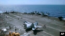 Crewmen of the U.S. aircraft carrier Theodore Roosevelt prepare their aircraft Tuesday, April 10,2018, in international waters off South China Sea. 