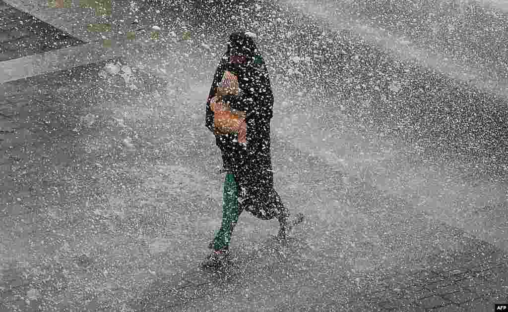 An Indian resident carrying a baby runs from waves on the promenade during a high tide in Mumbai.