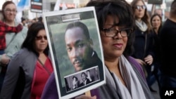 Val Scott holds up a photo of Martin Luther King Jr. during a march to mark the birthday of the slain civil rights leader in San Francisco, Jan. 15, 2018. 