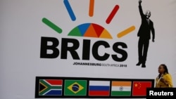 FILE - A delegate walks past a BRICS logo ahead of the 10th BRICS Summit, in Sandton, South Africa. 