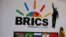 FILE - A delegate walks past a BRICS logo ahead of the 10th BRICS Summit, in Sandton, South Africa, July 24, 2018. 