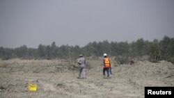 FILE - Construction workers walk along the island of Bhasan Char in the Bay of Bengal, Bangladesh, Feb. 14, 2018.