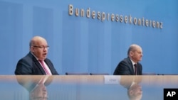 German Economy Minister Peter Altmaier, right, and Finance Minister Olaf Scholz brief the media during a news conference about German economy during the coronavirus crises in Berlin, Germany, Oct. 29, 2020.