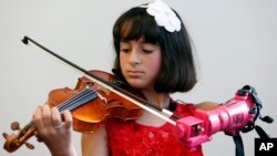 Isabella Nicola Cabrera, 10, plays her violin with her new prosthetic at the engineering department of George Mason University in Fairfax, Virginia, April 20, 2017. 