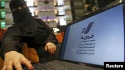 Saudi woman Fawzia al-Harbi, a candidate for local municipal council elections, shows her candidate biography at a shopping mall in Riyadh, Saudi Arabia, Nov. 29, 2015.