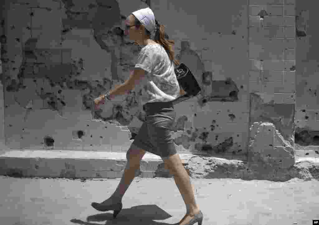 A woman walks past a damaged wall of a house of a house after a rocket fired by Palestinian militants hit in Ashdod, Israel, July 14, 2014.