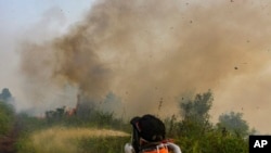 Firefighters spray water to extinguish brush fires in Kampar, Riau province, Indonesia, Sept. 11, 2019. 
