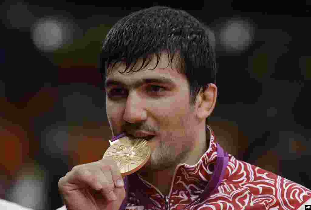Atlet Rusia, Tagir Khaibulaev, menggigit medali emas setelah memenangkan cabang judo nomor 100-kilogram putera (2/8). 