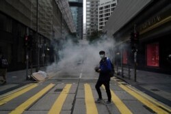 A man walks past as police use tear gas on protesters calling for electoral reforms and a boycott of the Chinese Communist Party in Hong Kong, Jan. 19, 2020.