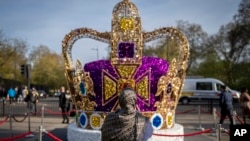 Une femme prend des photos d'une installation artistique représentant la couronne de Saint Édouard à Londres, le mercredi 3 mai 2023.