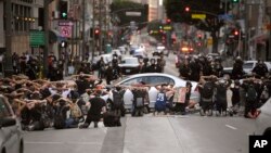 Demonstrators put their hands behind their heads before being taken into custody after the city's curfew went into effect following a protest, June 2, 2020, in Los Angeles over the death of George Floyd.
