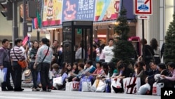 Para turis China beristirahat di pinggir jalan setelah berbelanja di daerah pertokoan mewah Ginza di Tokyo. (Foto: Dok)