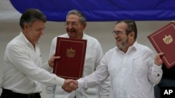 Presiden Kolombia, Juan Manuel Santos (kiri) dan pemimpin FARC Timoleon Jimenez berjabat tangan pada kesepakatan gencatan senjata di Havana, Kuba hari Kamis (23/6). 