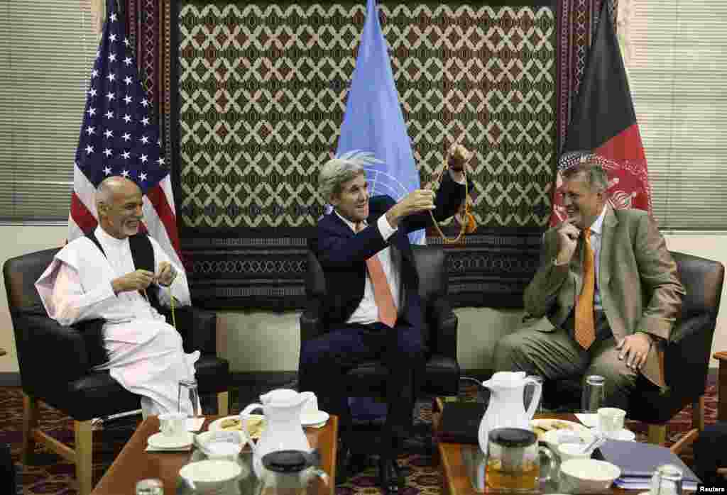 U.S. Secretary of State John Kerry (center) holds up a string of Islamic beads, as Afghanistan&#39;s presidential candidate Ashraf Ghani Ahmadzai (left) and Jan Kubis, the U.N. Secretary-General&#39;s special representative look on, during a meeting at the U.S. embassy in Kabul, Aug. 8, 2014.