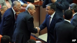 Ismet Yilmaz, the ruling Justice and Development Party's candidate and the Defense Minister in the outgoing government (C-R) shakes hands with the Nationalist Movement Party leader Devlet Bahceli at the Parliament after his election as the new Speaker in Ankara, July 1, 2015.