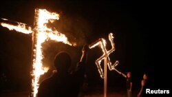 Seorang anggota kelompok nasionalis kulit putih membakar lambang swastika dan salib di luar Kota Atkins, Arkansas, 9 Maret 2019. 