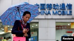 지난 2012년 중국 상하이 시내에서 우산을 쓰고 지나가는 여성 뒤로 차이나모바일 로고가 보인다. 