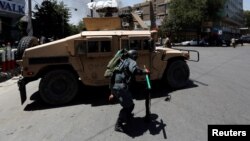 Seorang anggota polisi Afghanistan melindungi dirinya saat asap membumbung dari lokasi serangan di Kabul, Afghanistan, 31 Juli 2017 (foto: REUTERS/Mohammad Ismail)