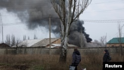 Volodymyr (61) dan Nataliia Bolias (51), berjalan melewati sebuah bangunan industri terkena serangan rudal pada Hari Natal di garis depan di Bakhmut, Ukraina, 25 Desember 2022. (REUTERS/Clodagh Kilcoyne)