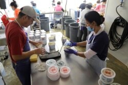 Francisco Munoz Nava, left, a guest migrant worker from Hidalgo, Mex., and his sister Minerva Munoz Nava weigh and package crab meat, May 14, 2020, in Fishing Creek, Md.