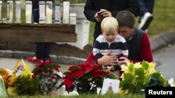 Seorang pria memeluk anaknya saat menghadiri acara penghormatan untuk korban penembakan massal di Newton, Connecticut (16/12). (Reuters/Lucas Jackson)