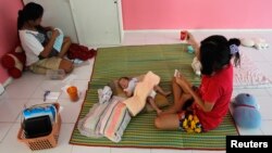 FILE: A 16-year-old mother, right, rests with her one-month-old son at the Association for the Promotion of the Status of Women, Bangkok.