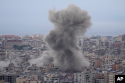 FILE - Asap mengepul di antara gedung-gedung yang terkena serangan udara Israel di Dahiyeh, di pinggiran selatan Beirut, Lebanon, 17 November 2024.