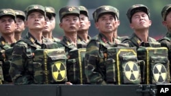 FILE - North Korean soldiers ride on a truck during a military parade as they hold packs marked with the nuclear symbol in Pyongyang, North Korea, July 27, 2013.