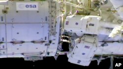 In this photo provided by NASA, NASA astronaut Anne McClain and Canadian astronaut David Saint-Jacques tackle battery and cable work outside the International Space Station, April 8, 2019.