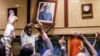 People remove, from the wall at the International Conference centre, where parliament had their sitting, the portrait of former Zimbabwean President Robert Mugabe after his resignation on November 21, 2017, in Harare. Robert Mugabe resigned as president of Zimbabwe on November 21, 2017 swept from power as his 37-year reign of brutality and autocratic control crumbled within days of a military takeover. The bombshell news was delivered by the parliament speaker to a special joint session of the assembly which had convened to impeach Mugabe, 93, who has dominated every aspect of Zimbabwean public life since independence in 1980. AFP PHOTO /Jekesai NJIKIZANA