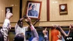 មនុស្ស​ម្នា​ដក​រូប​របស់​លោក​ប្រធានាធិបតី​ស៊ីមបាវ៉េ Robert Mugabe ពី​មជ្ឈមណ្ឌល International Conference កាលពី​ថ្ងៃទី២១ ខែវិច្ឆិកា ឆ្នាំ២០១៧ ក្នុង​ក្រុង Harare។