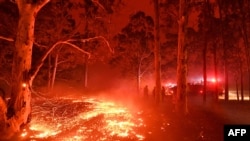 Burning embers cover the ground as firefighters battle bushfires around Nowra in New South Wales, Australia, Dec. 31, 2019. Thousands of holidaymakers and locals fled to beaches in southeast Australia, Dec. 31, as blazes left no escape by land.