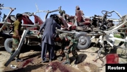 Petugas keamanan mengumpulkan bukti-bukti di dekat kendaraan yang hancur akibat ledakan bom di Quetta (23/5). Sedikitnya 11 personel keamanan dan dua warga sipil tewas dalam insiden tersebut.