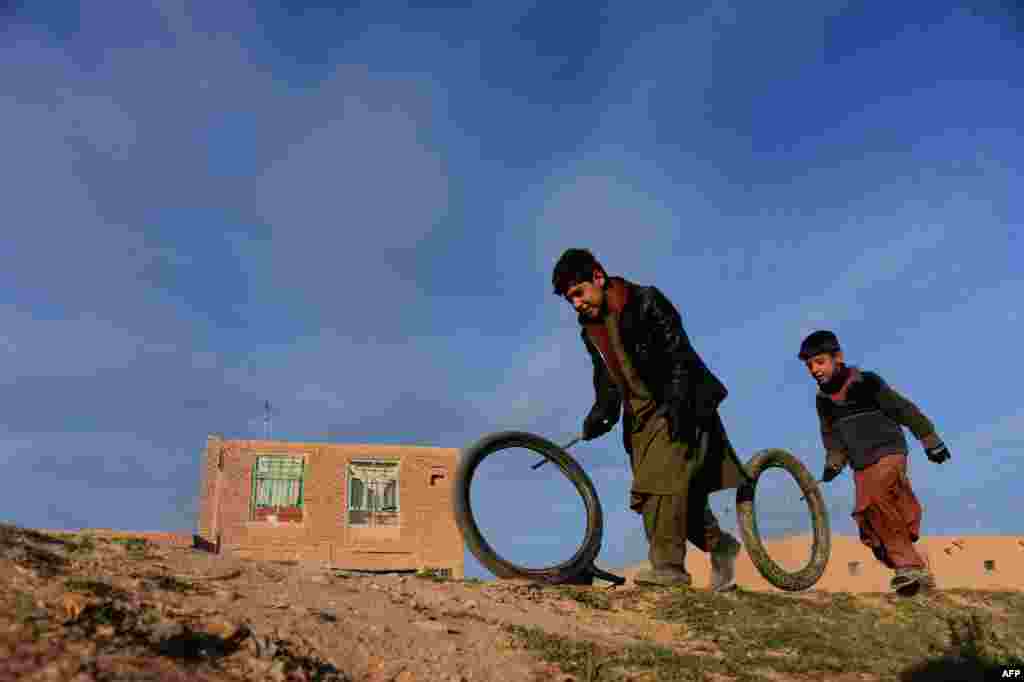 Dua anak Afghanistan bermain dengan ban bekas di pinggiran kota Herat.